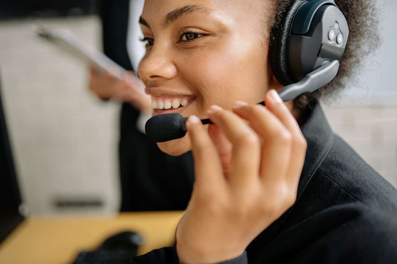 Operatrice call center con cuffie e microfono sorridente durante una chiamata di telemarketing outbound